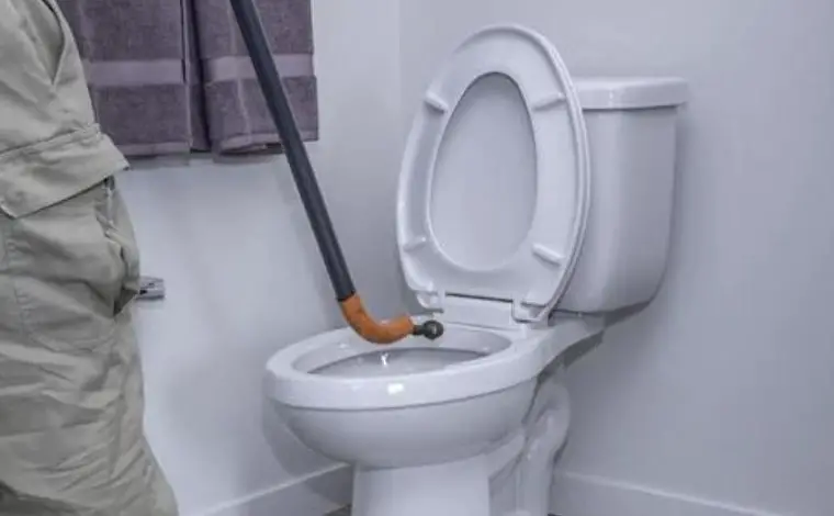 Uncloging a toilet with a toilet auger